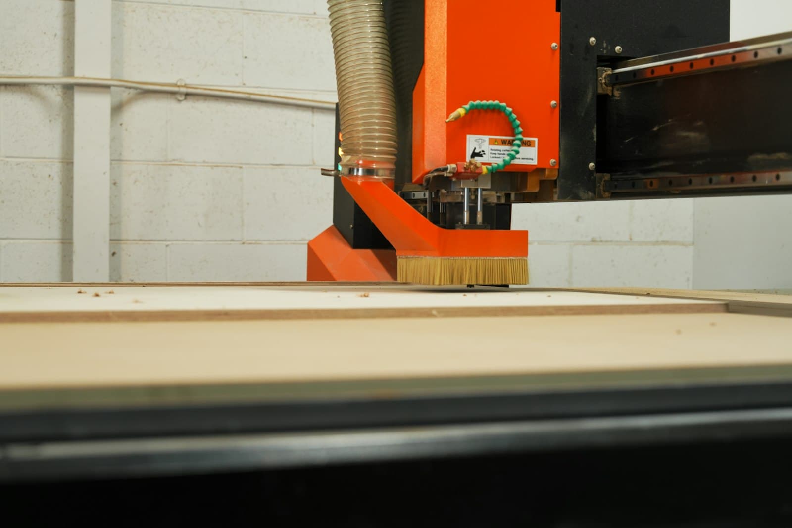 A CNC router machining a wood panel on a furniture production line