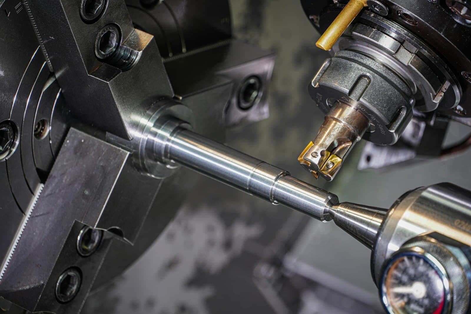 A steel rod held in a lathe chuck being machined by a cutting tool